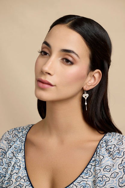 Model with dark hair in a blue, white and black patterned dress wearing Sterling Silver Handmade Pearl Heart Drop Earring With 18 carat Vermeil Detail