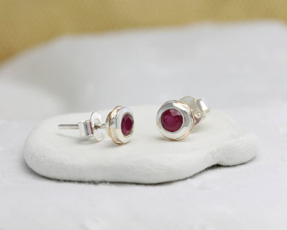 Sterling Silver Ruby & 14 carat Gold Detail Studs on a white cushion