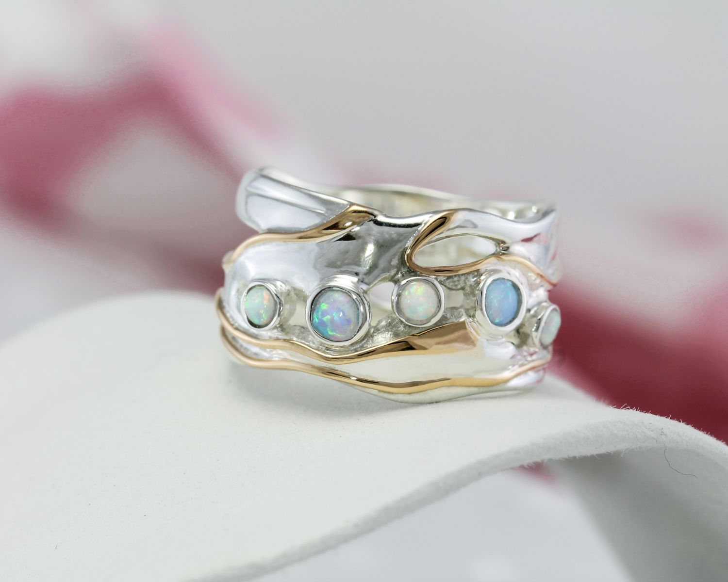 Silver ring with opal stones on a white surface