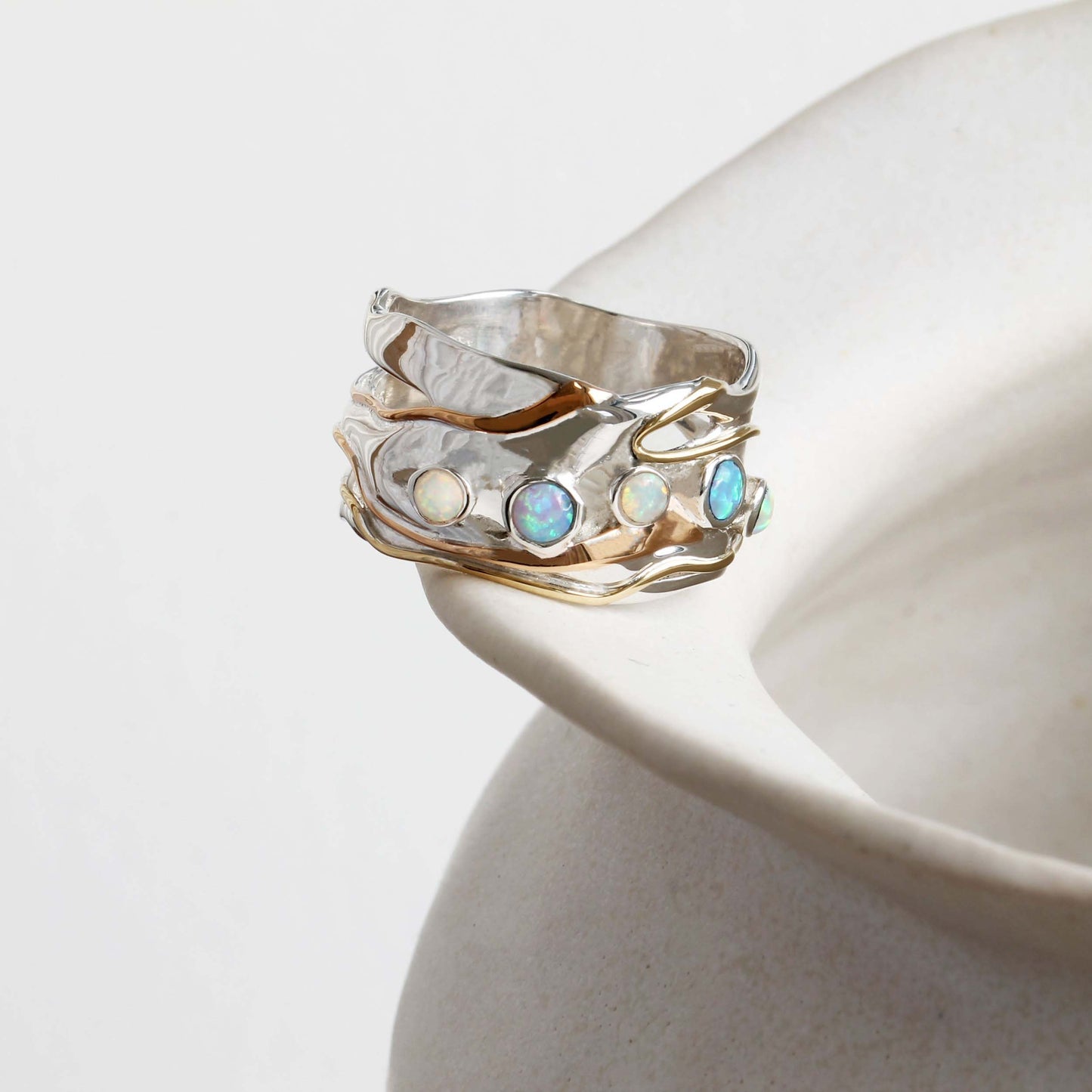Silver ring with opal stones on a white ceramic surface