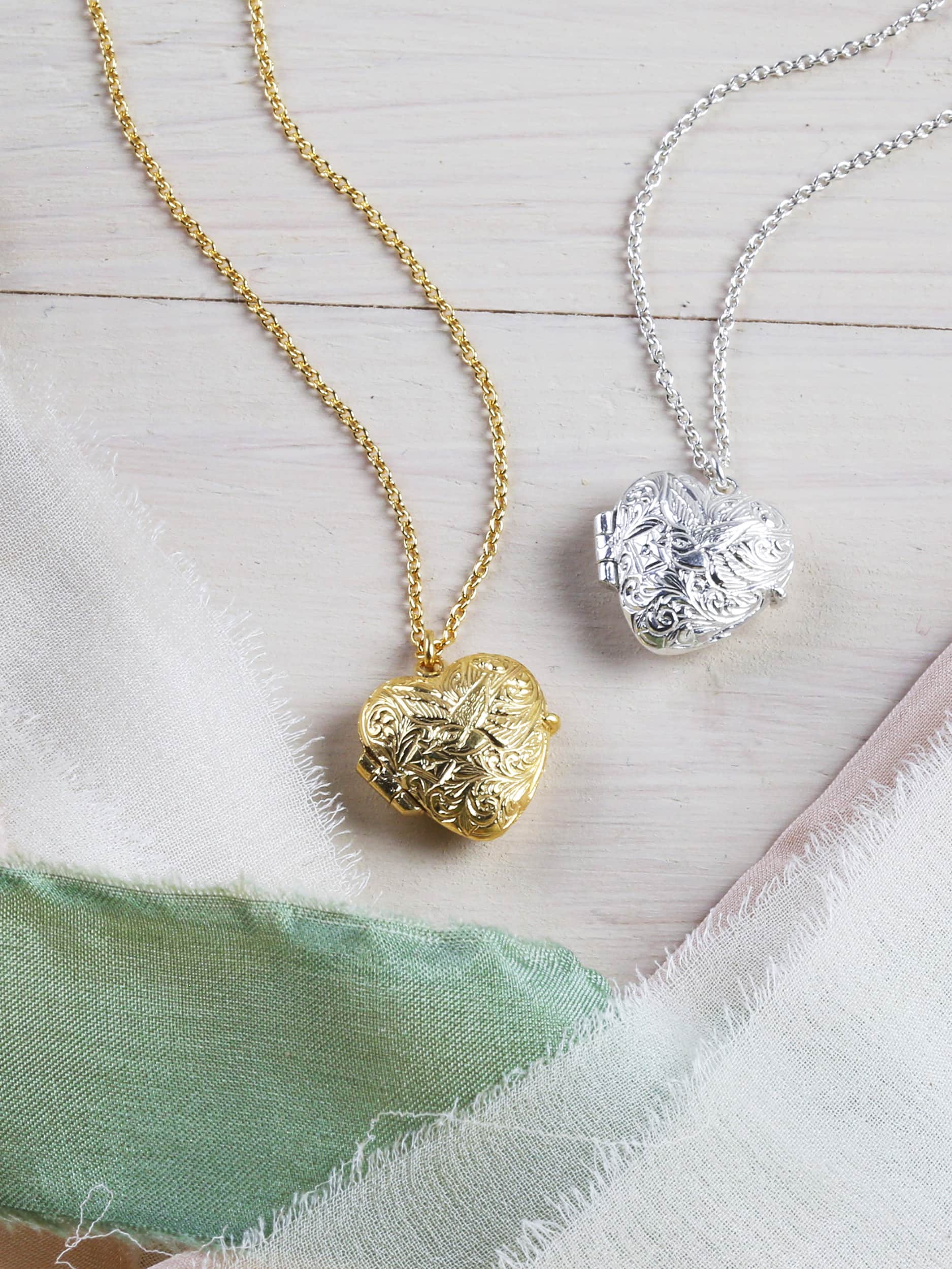 Gold and silver heart-shaped pendants on chains with a fabric background