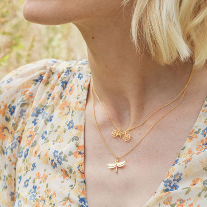 Woman wearing two gold necklaces with a floral patterned top
