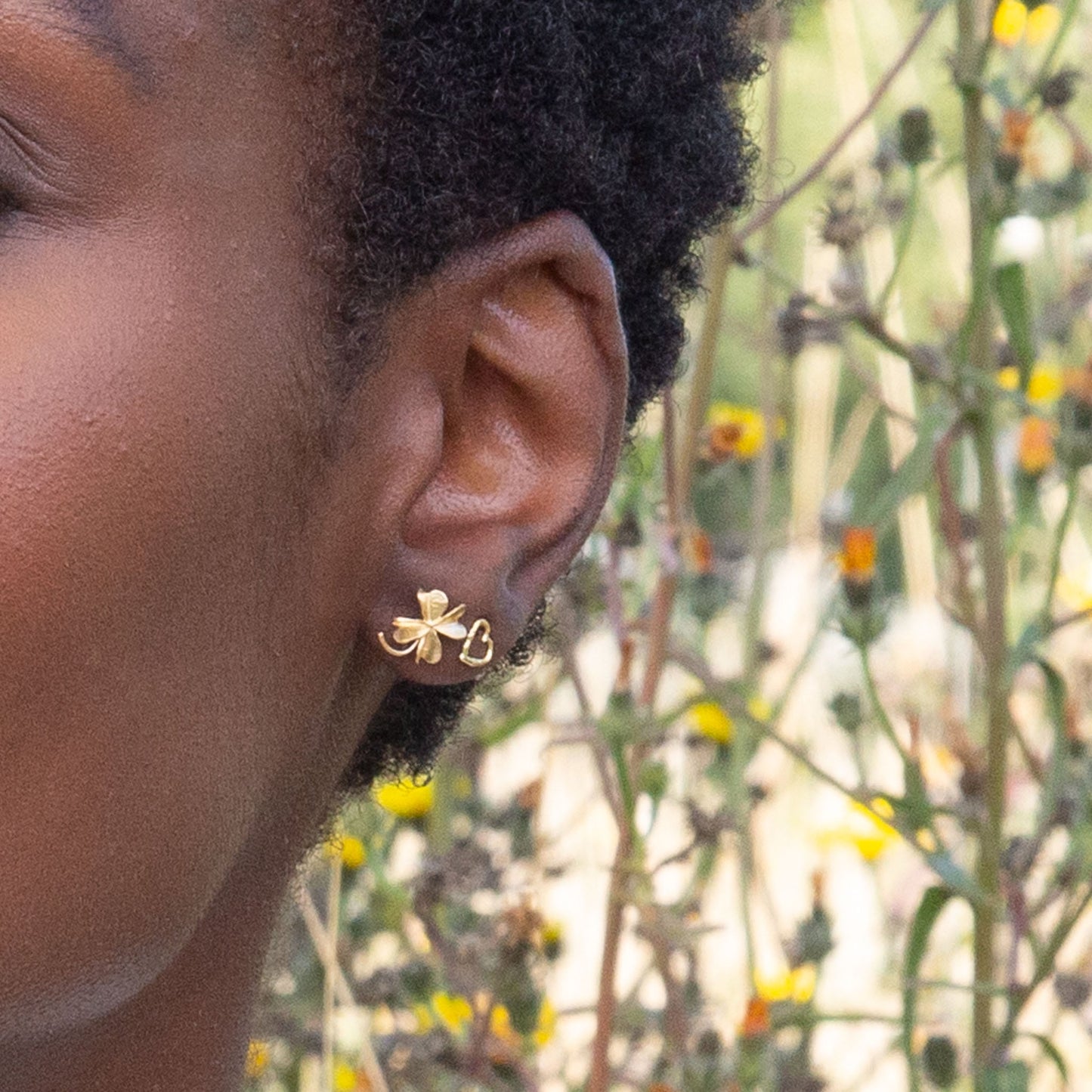 Close-up of a person's ear with a gold earring against a natural background