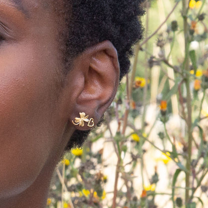 Close-up of a person's ear with a gold earring against a natural background