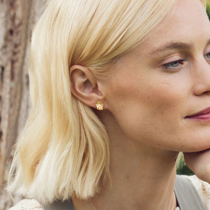 Close-up of a woman with blonde hair wearing a gold earring.